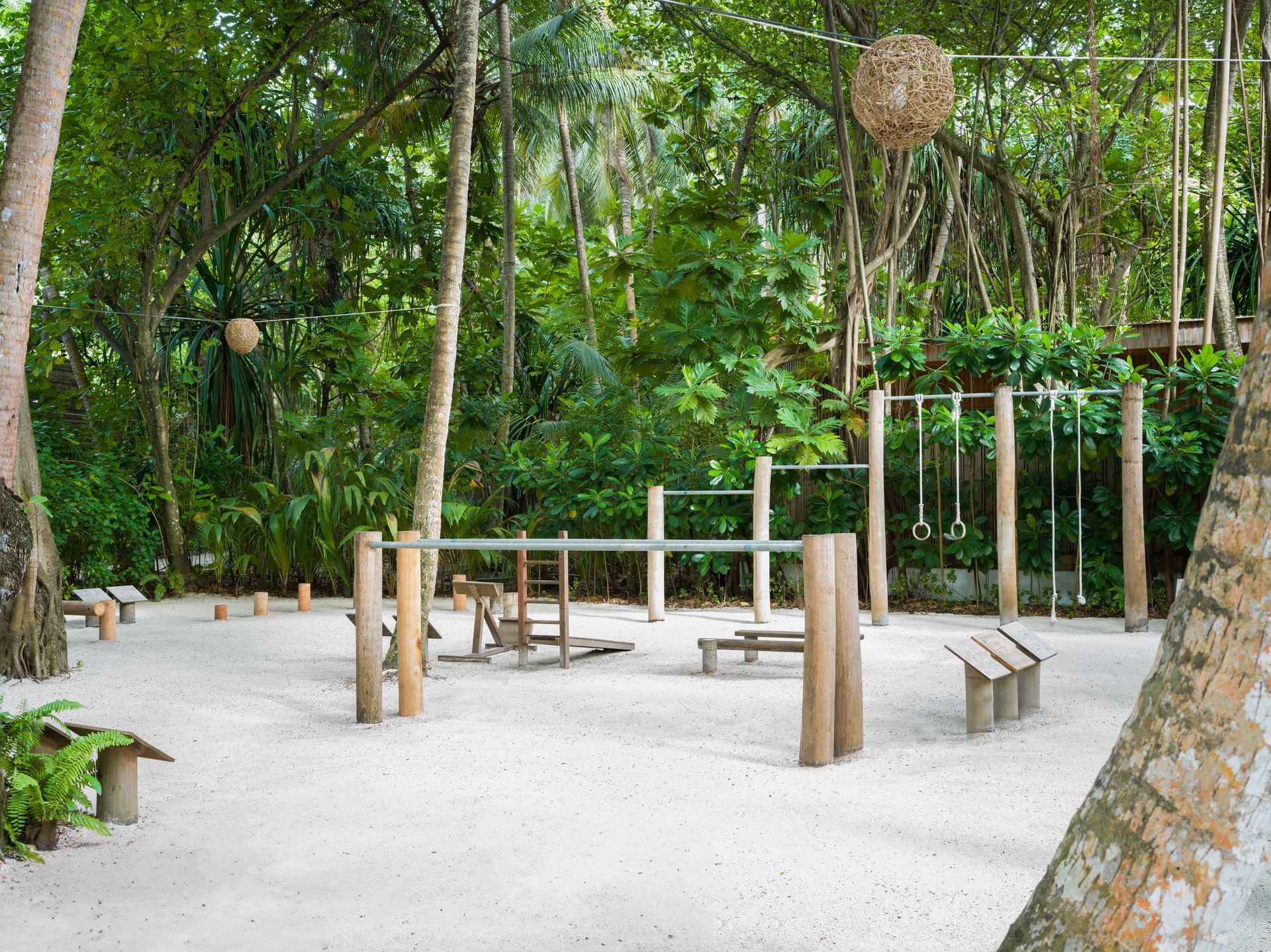 A wooden playground in the middle of a forest surrounded by trees.