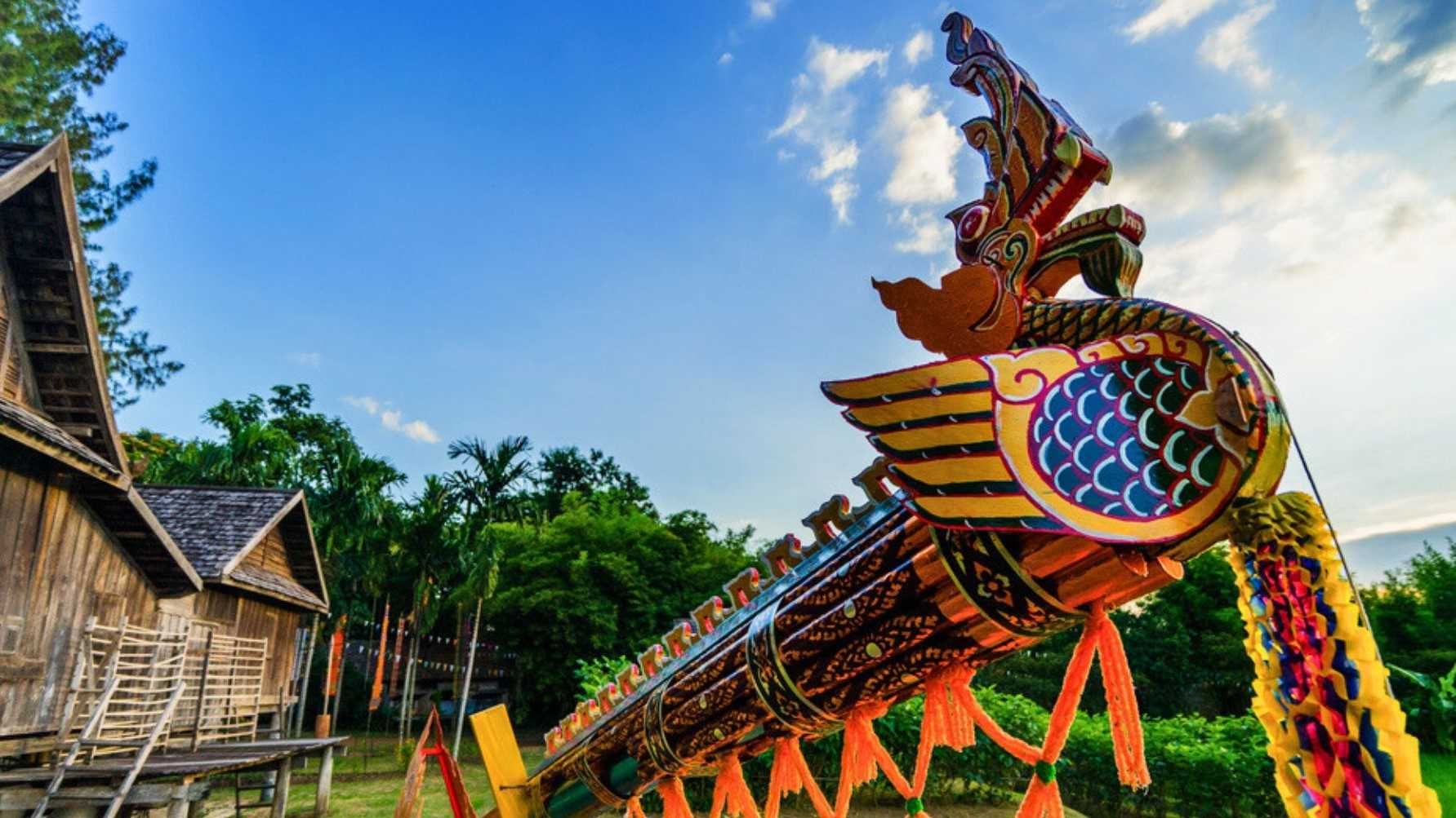 A colorful statue of a dragon is sitting in front of a wooden house.