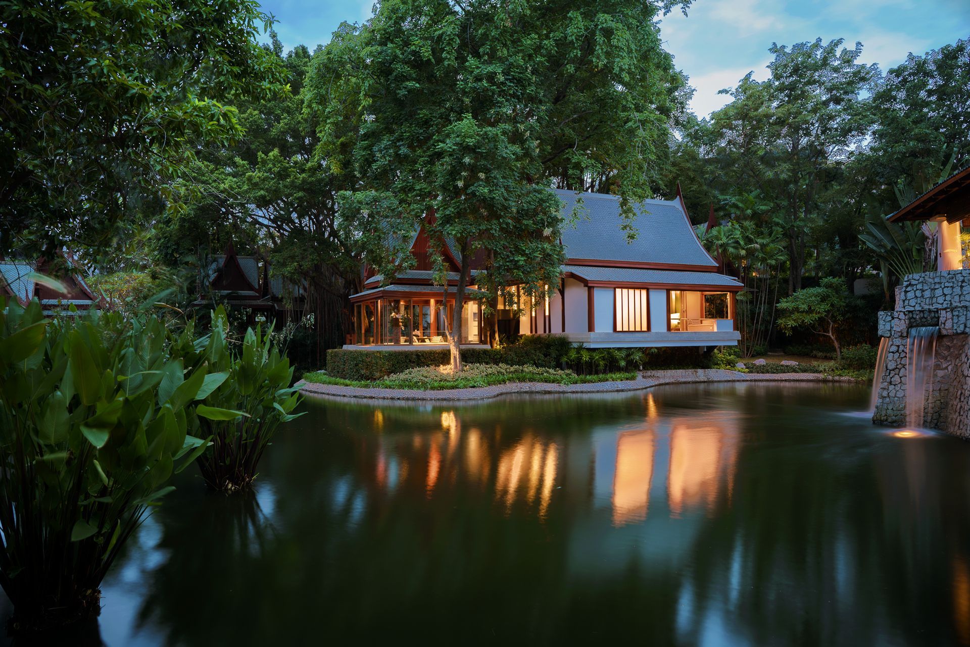 A house is sitting on a small island in the middle of a lake surrounded by trees.