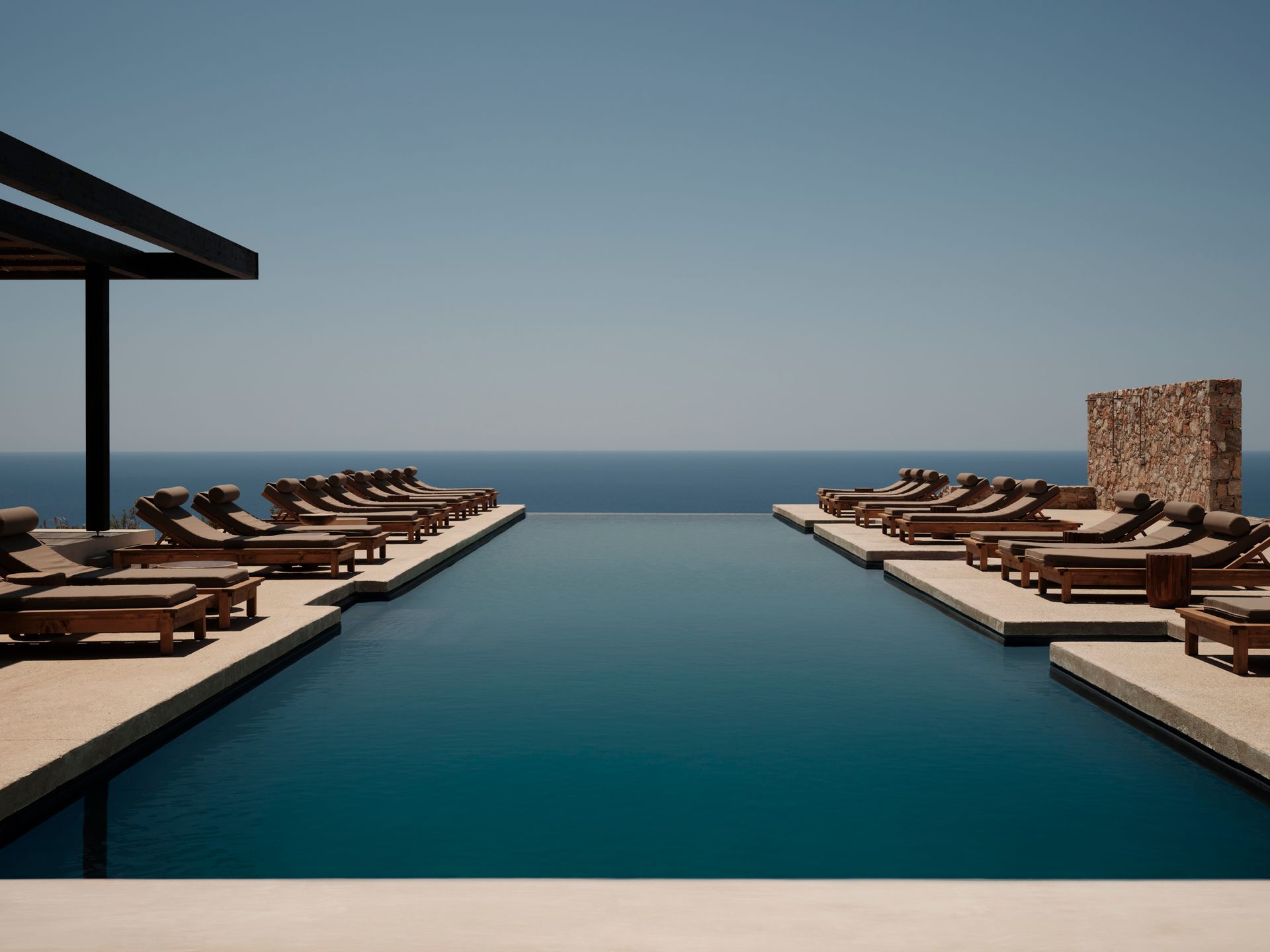 Infinity pool with ocean view and rows of lounge chairs.