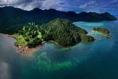 Aerial view of lush green tropical Malaysian islands surrounded by turquoise ocean and dark clouds
