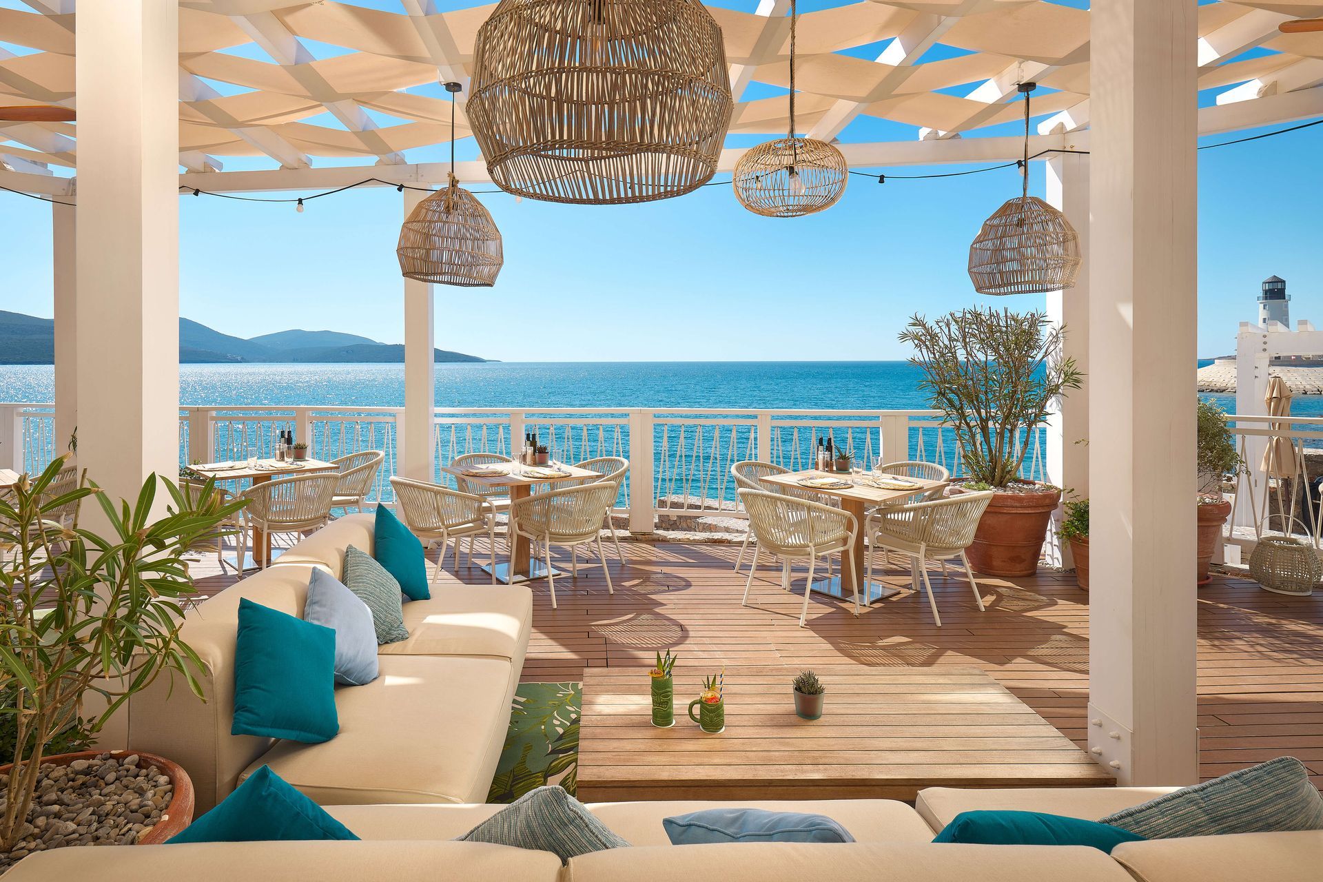 A restaurant with a view of the ocean and tables and chairs.