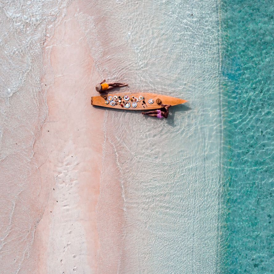 An aerial view of a group of people in a boat on a beach.