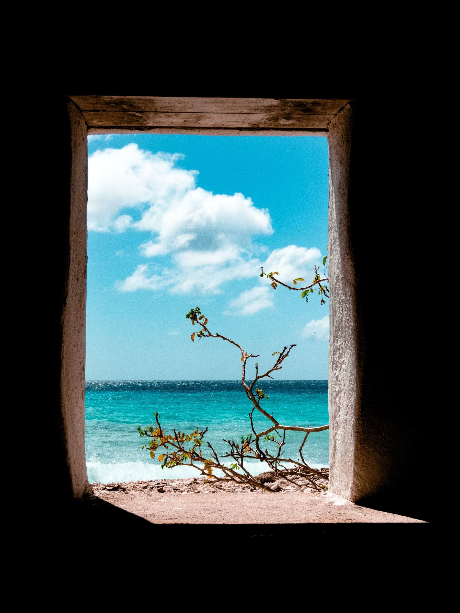 A window with a view of the ocean and a lighthouse