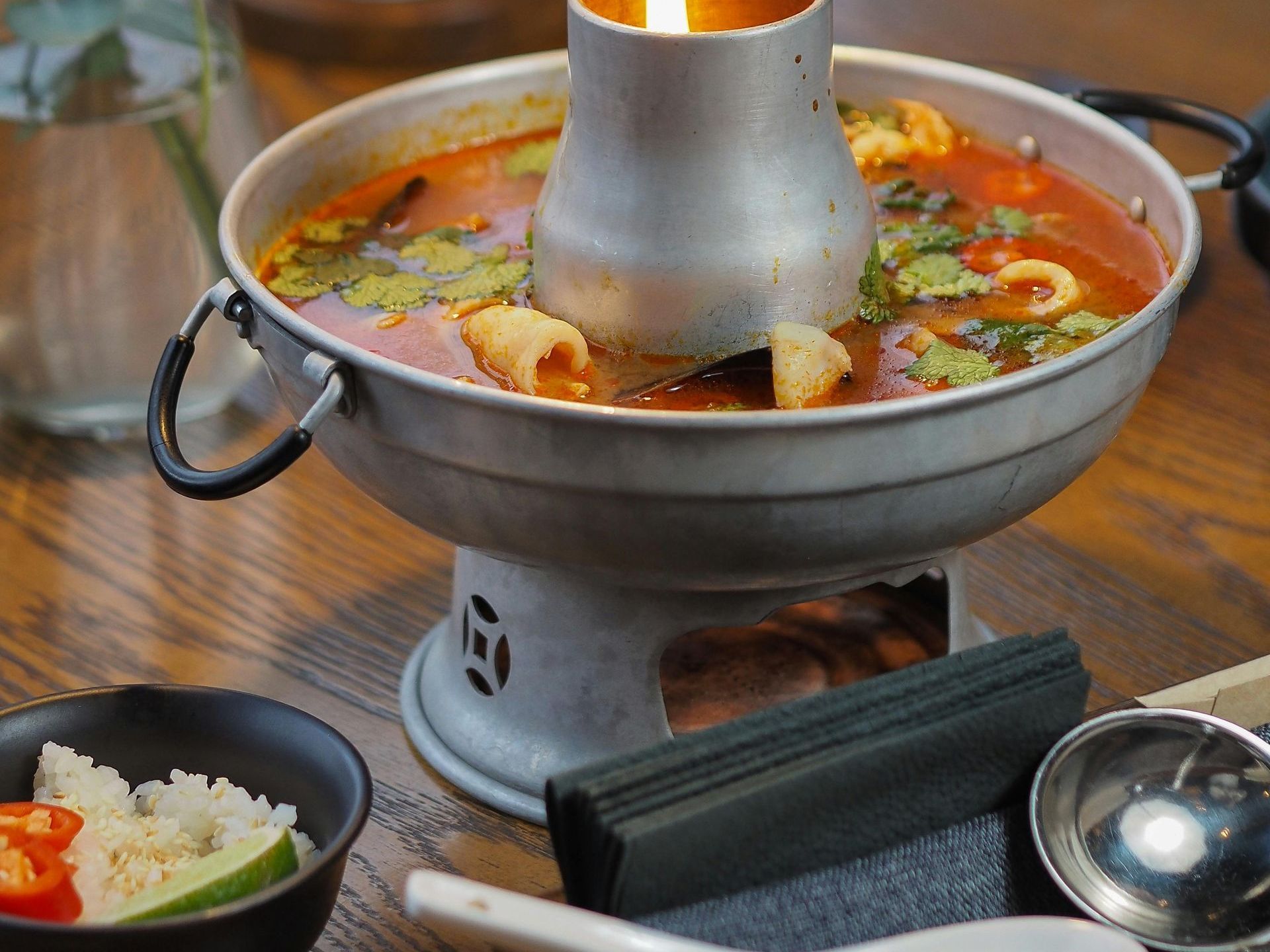 A pot of soup is sitting on a wooden table.