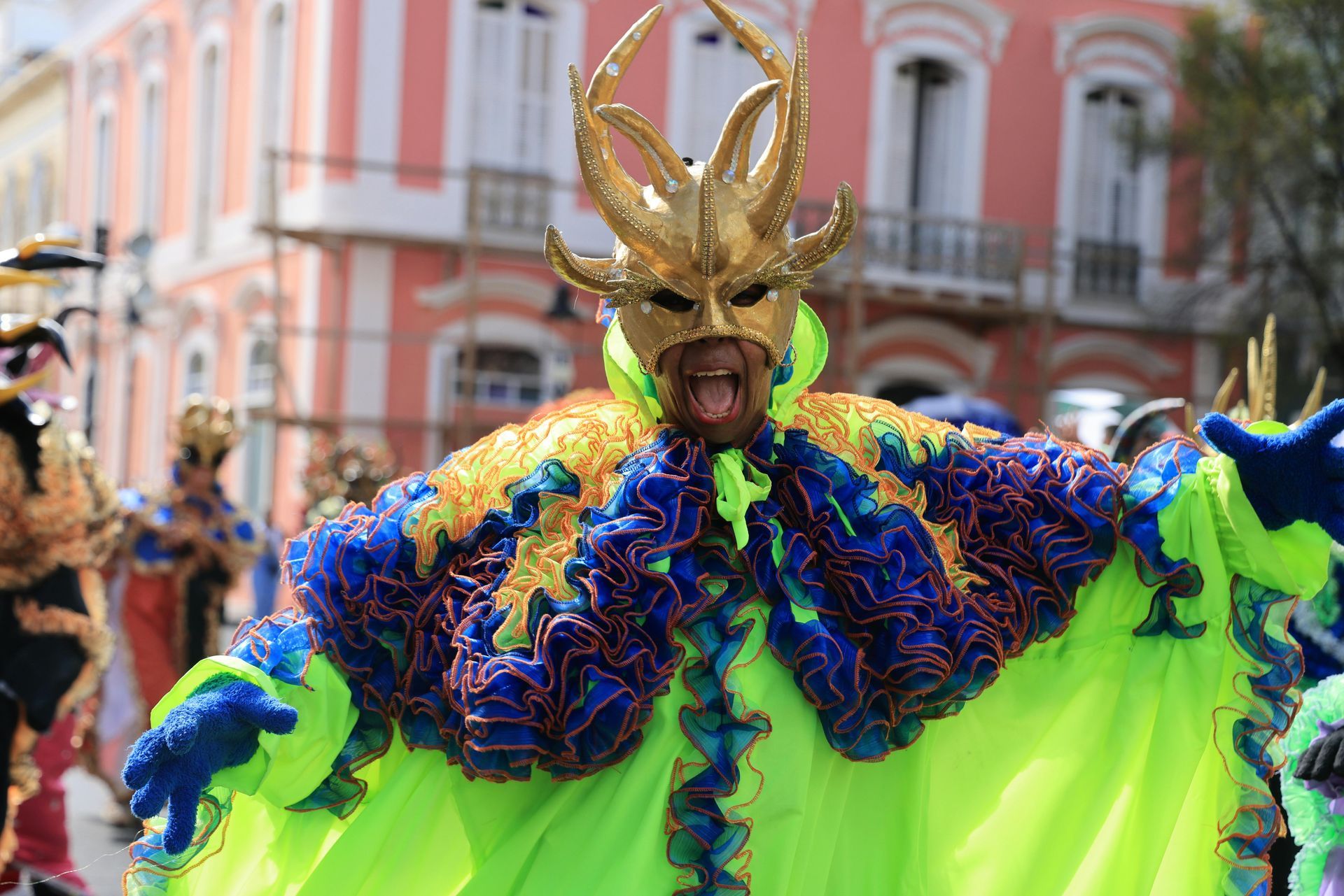 A man in a colorful costume is standing in front of a building.