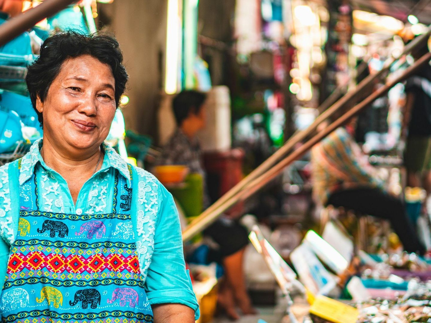 A woman is standing in a crowded market and smiling.