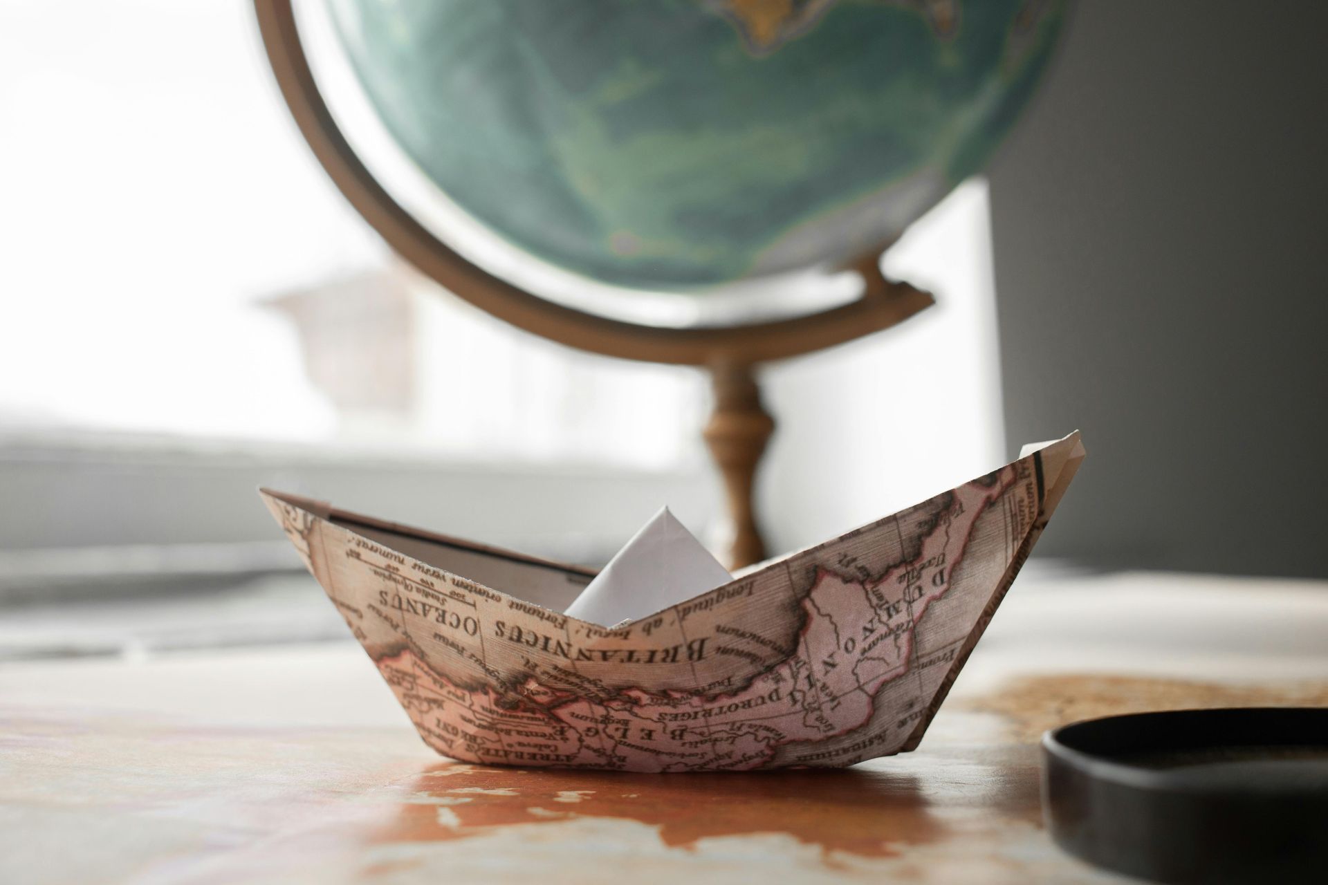 How to Travel Sustainably paper boat and globe