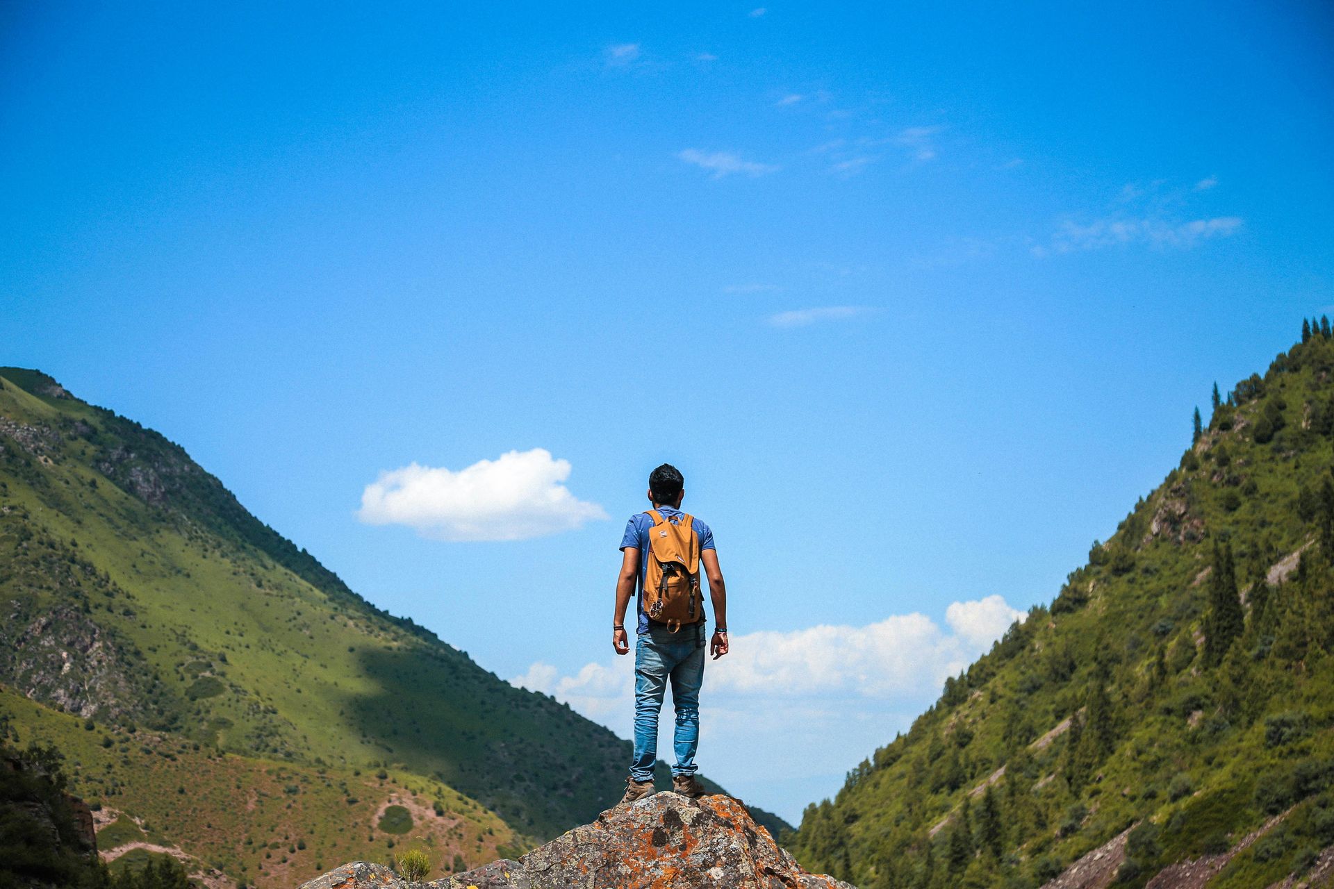 A man with a backpack is standing on top of a mountain.