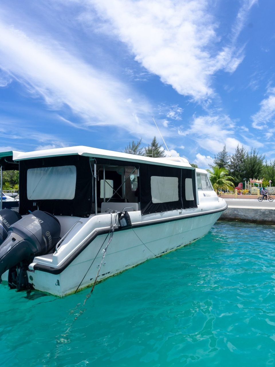 A white boat is docked in the water near a dock.