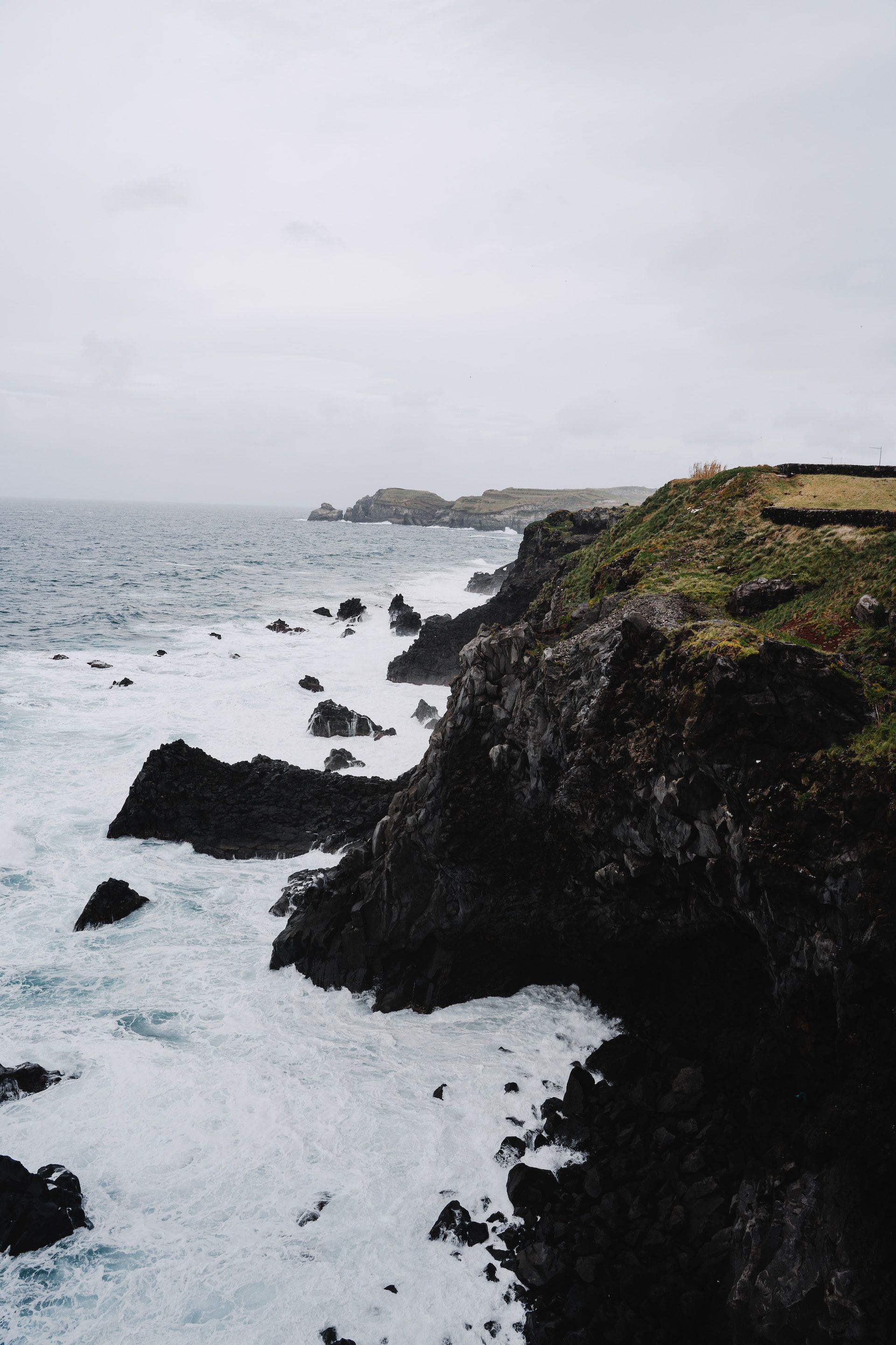 A rocky cliff overlooking the ocean on a cloudy day.
