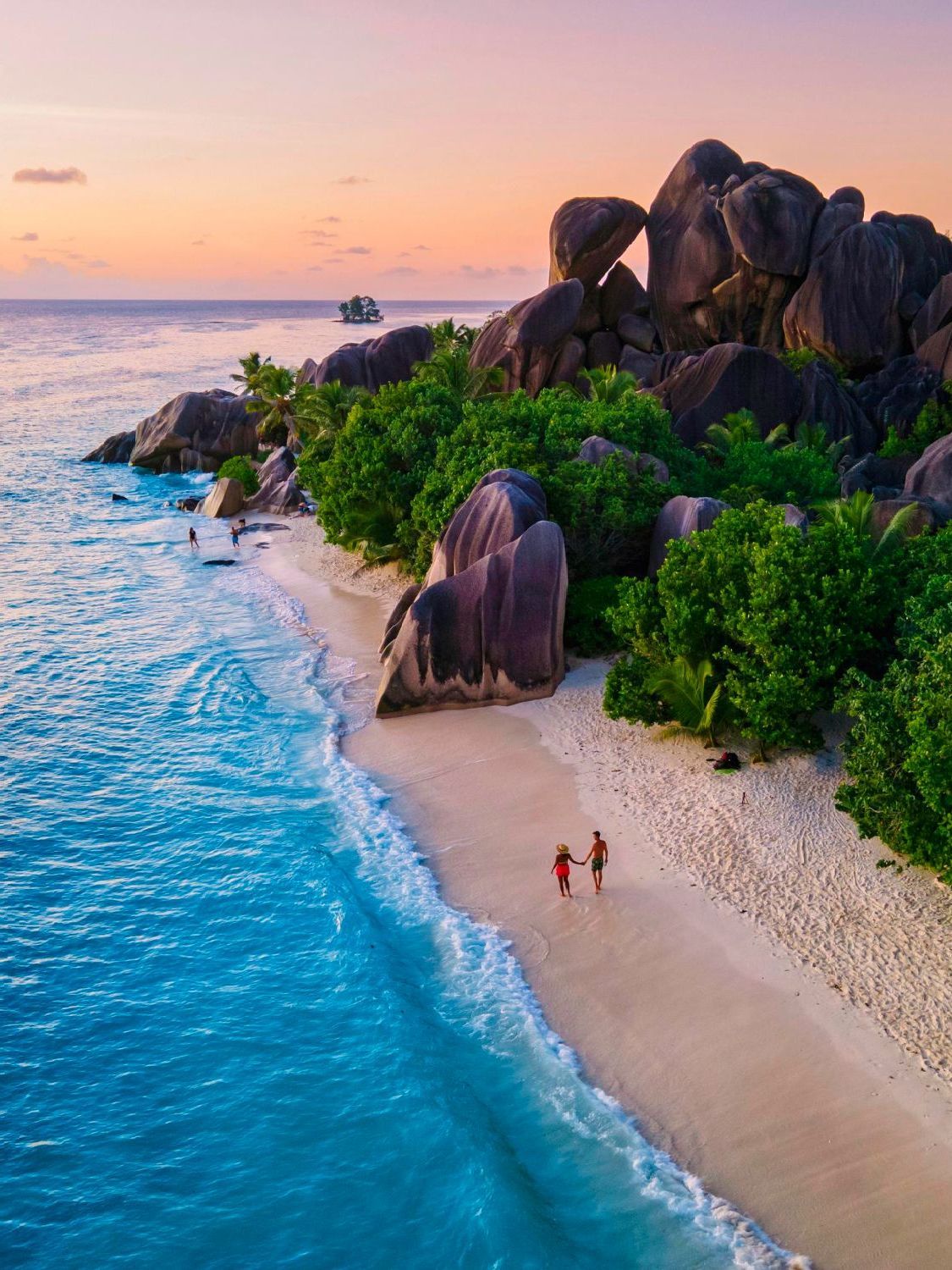 An aerial view of a couple walking on a beach.