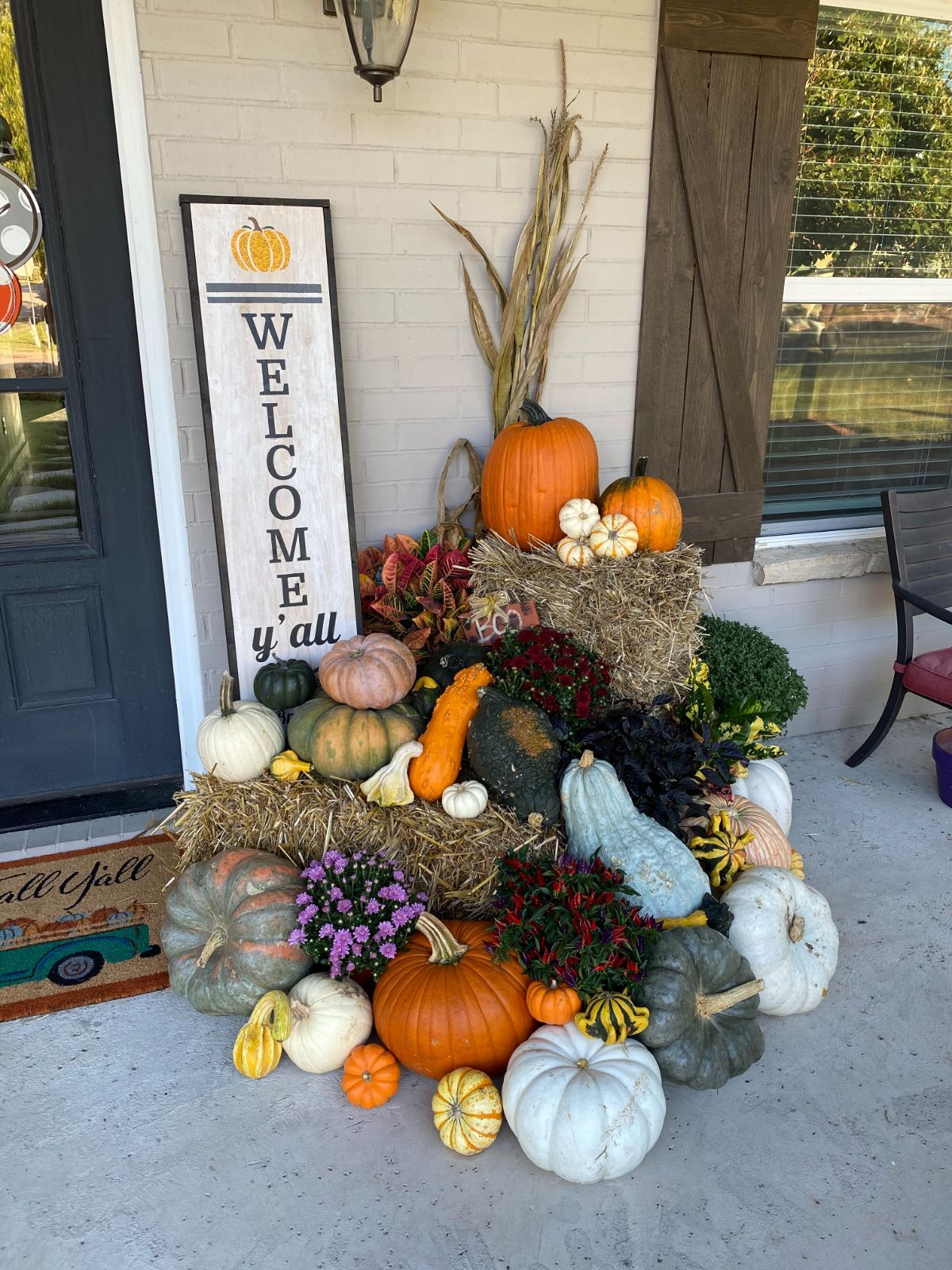 Fall porch display with pumpkins, hay bales, and 