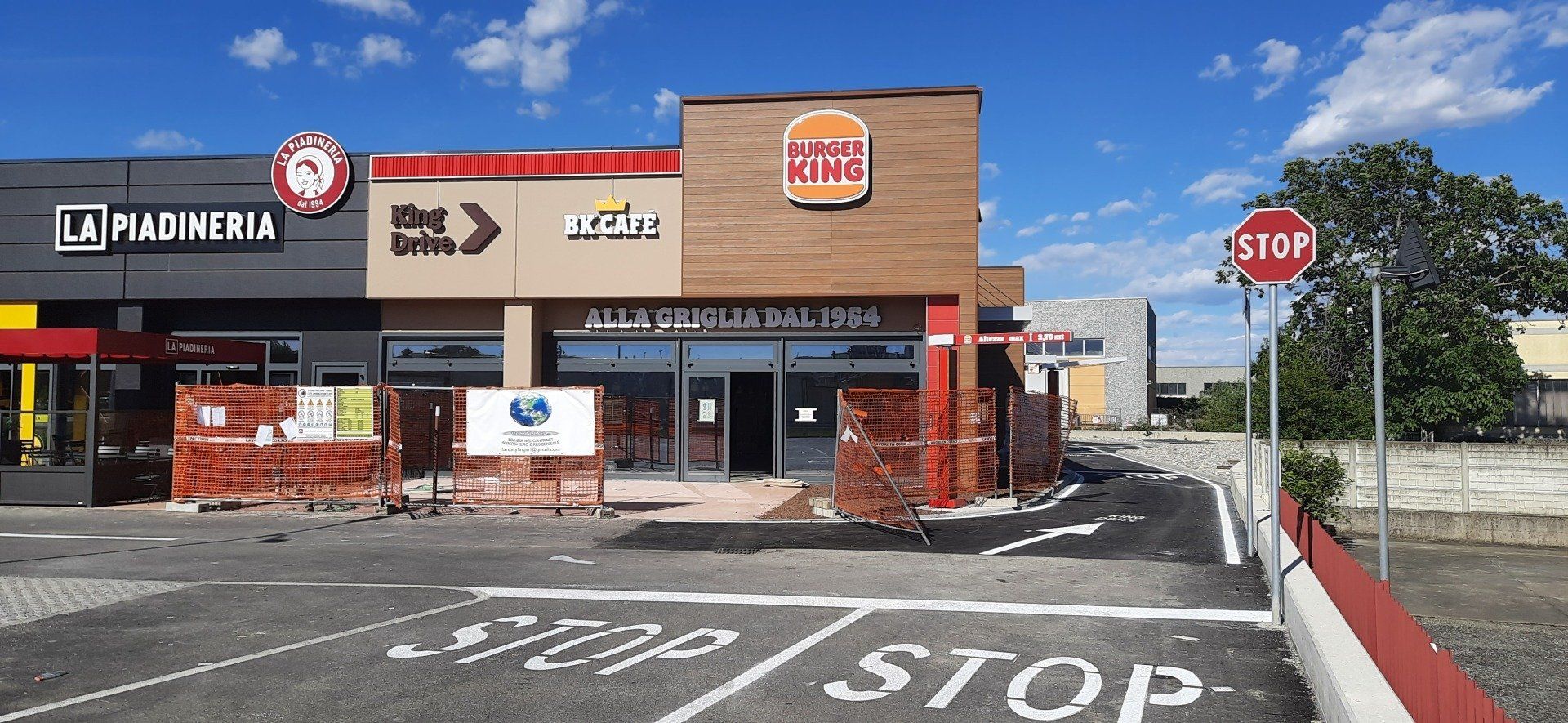 Un ristorante Burger King in costruzione accanto ad altre attività commerciali, con un segnale di stop in primo piano.