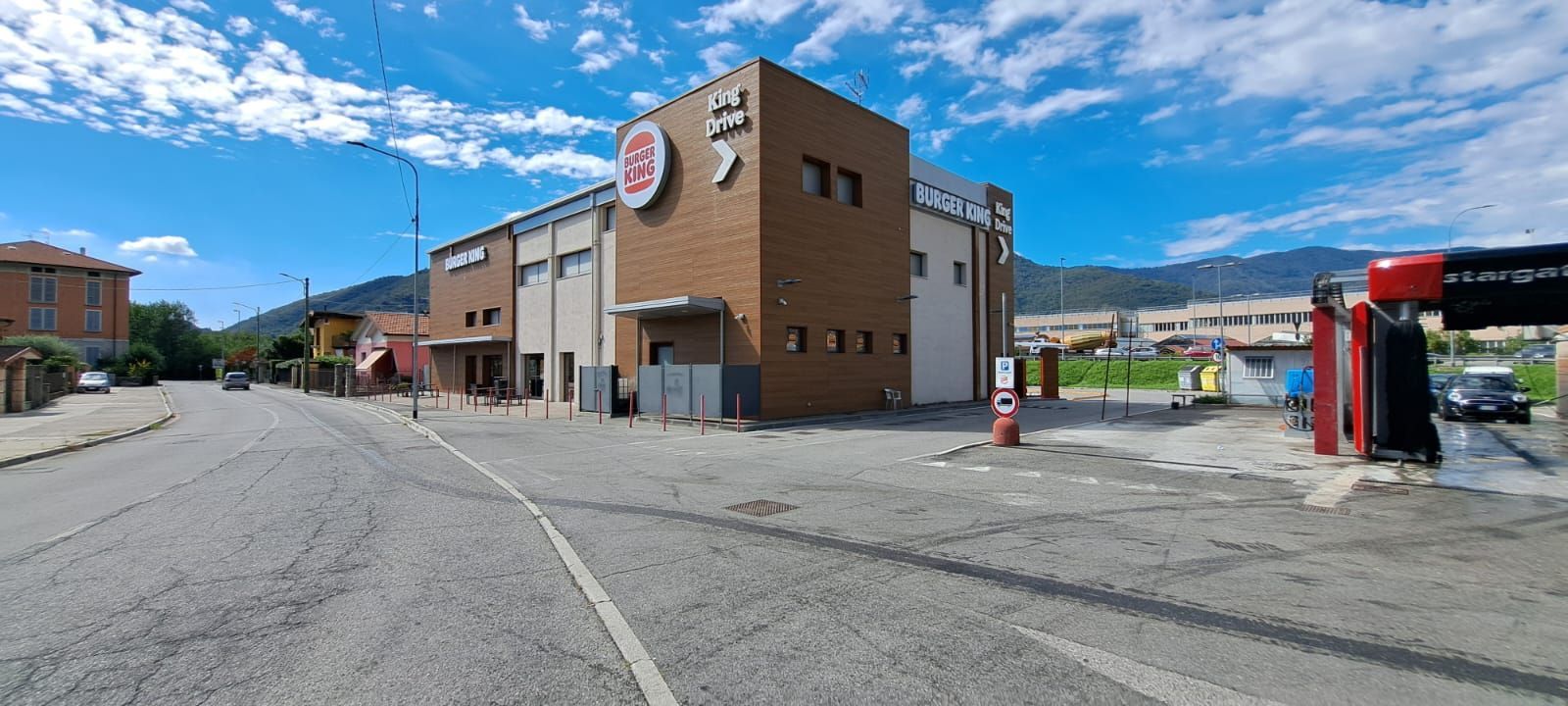 Una scena di strada con un edificio marrone e un autolavaggio sotto un cielo azzurro.