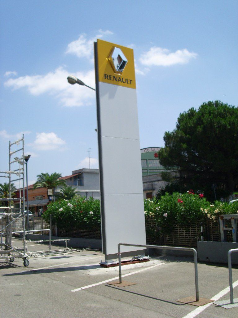 Grande cartello bianco della Renault con logo e testo, in una giornata di sole.