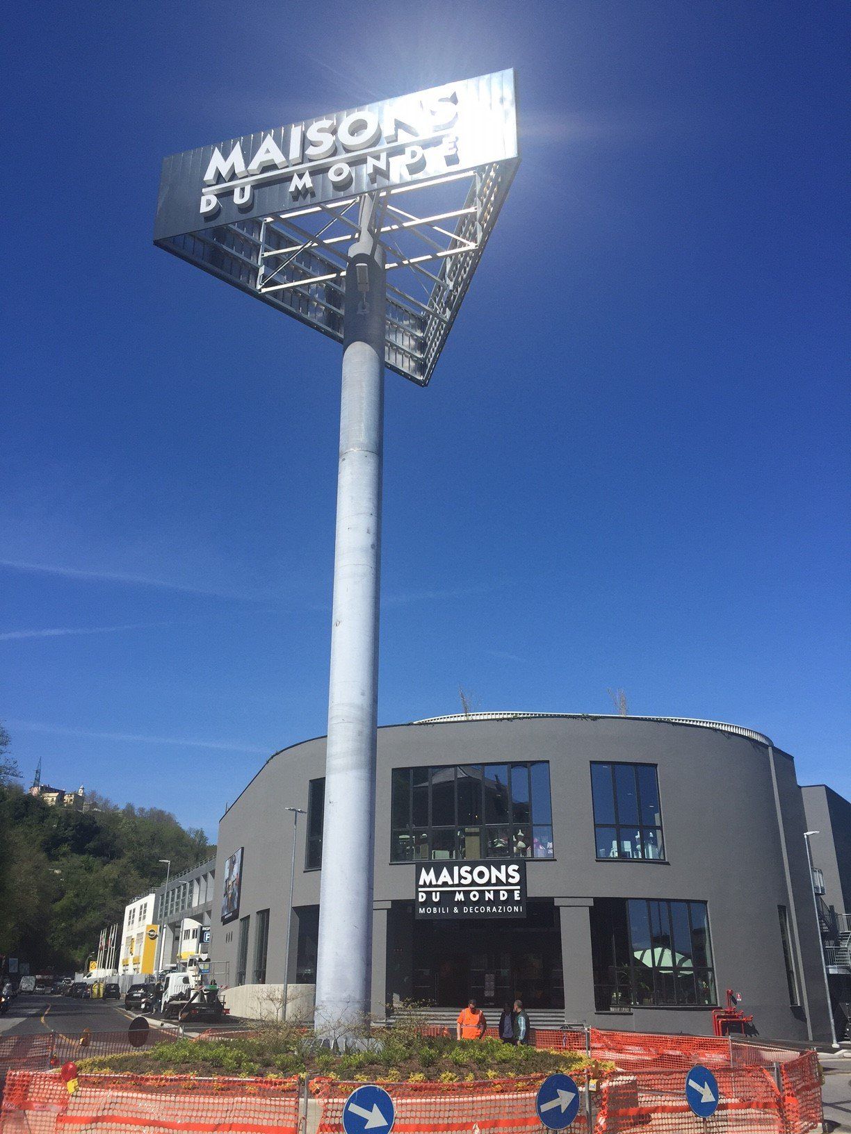 Un'alta insegna della Maisons du Monde sopra un edificio grigio, sullo sfondo di un cielo azzurro brillante.