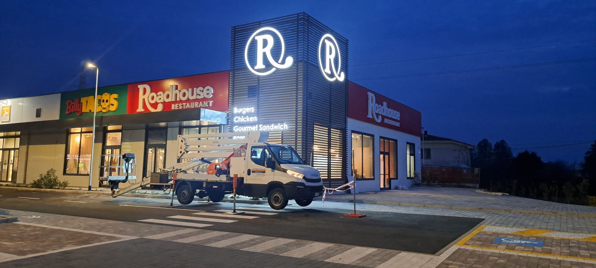 Un ristorante Roadhouse al tramonto con un veicolo parcheggiato davanti. L'insegna ha una grande 