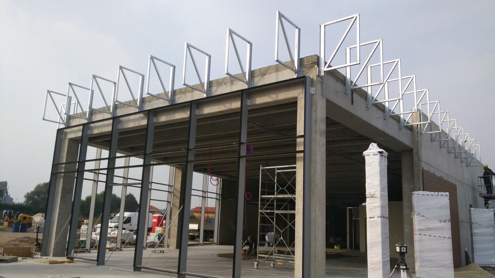 Cantiere: edificio in cemento con struttura metallica, sotto un cielo nuvoloso.