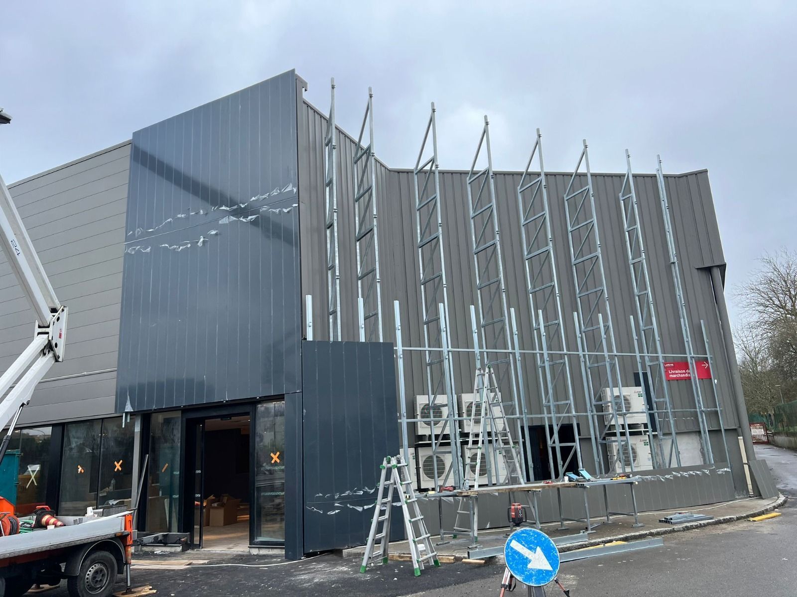 Edificio in costruzione: esterno con facciata grigio scuro, struttura metallica e unità di aria condizionata.