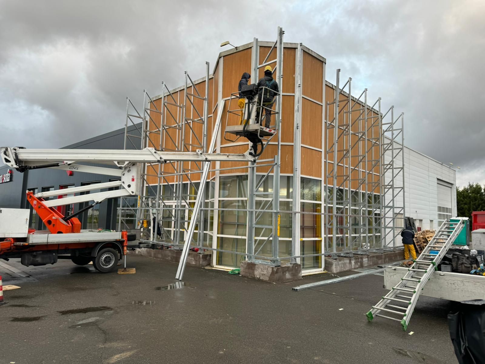 Operai edili su impalcature, impegnati nella riparazione dell'esterno di un edificio; cielo nuvoloso.