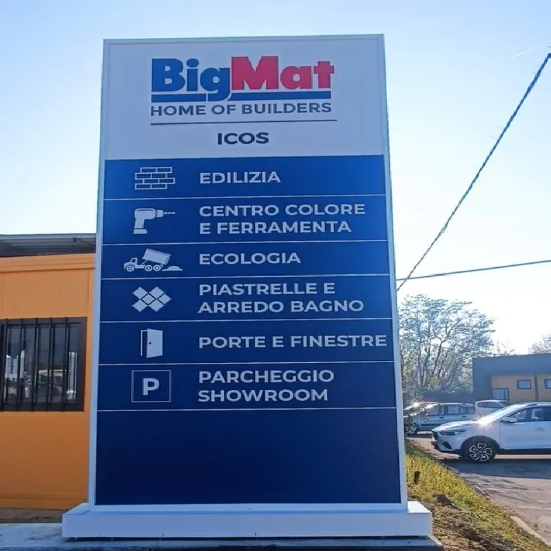 Insegna per il negozio BigMat, blu e bianca, con icone e testo che elencano reparti come