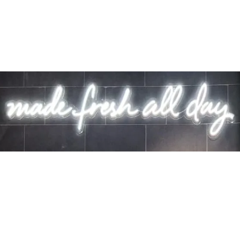 Insegna al neon bianca su sfondo di piastrelle scure, con la scritta 