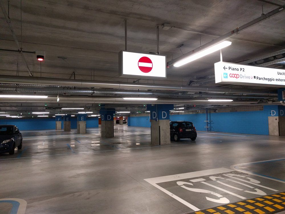 Parcheggio vuoto con dettagli blu, segnale di stop e divieto di accesso.