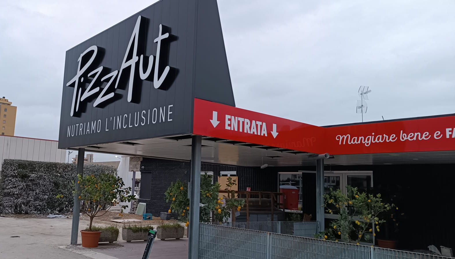 L'ingresso di una pizzeria con un'insegna nera con la scritta 
