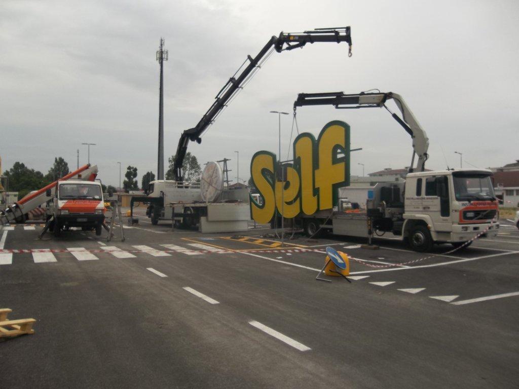 Due gru sollevano un grande graffito con la scritta 