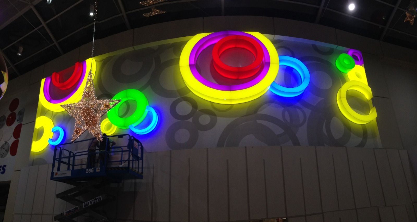 Persona sull'ascensore che lavora su cerchi colorati e illuminati e su una parete con stelle.