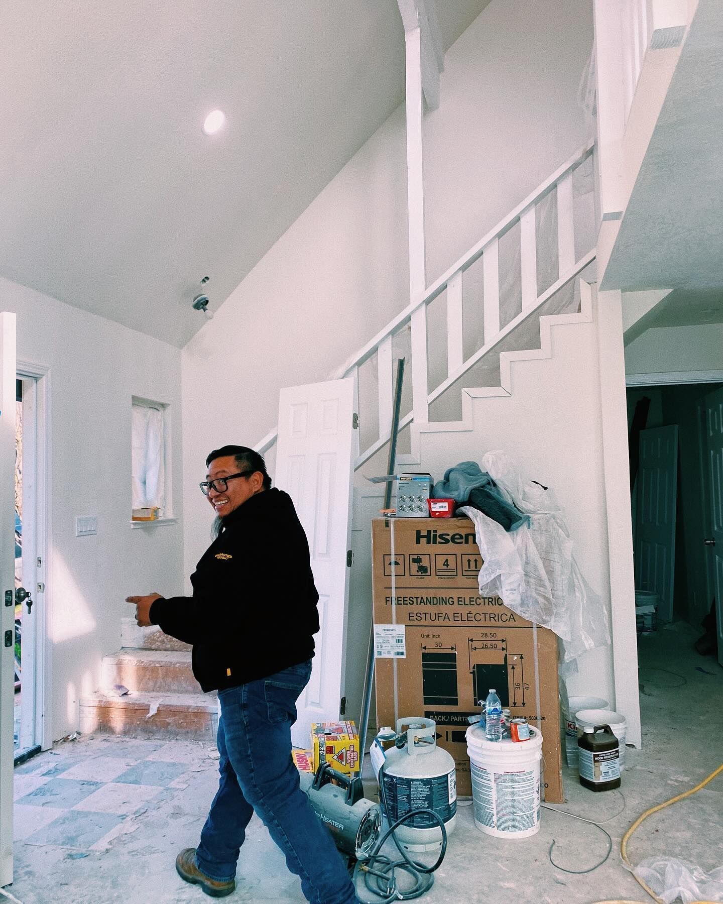 a man in a black jacket is walking in a room with stairs