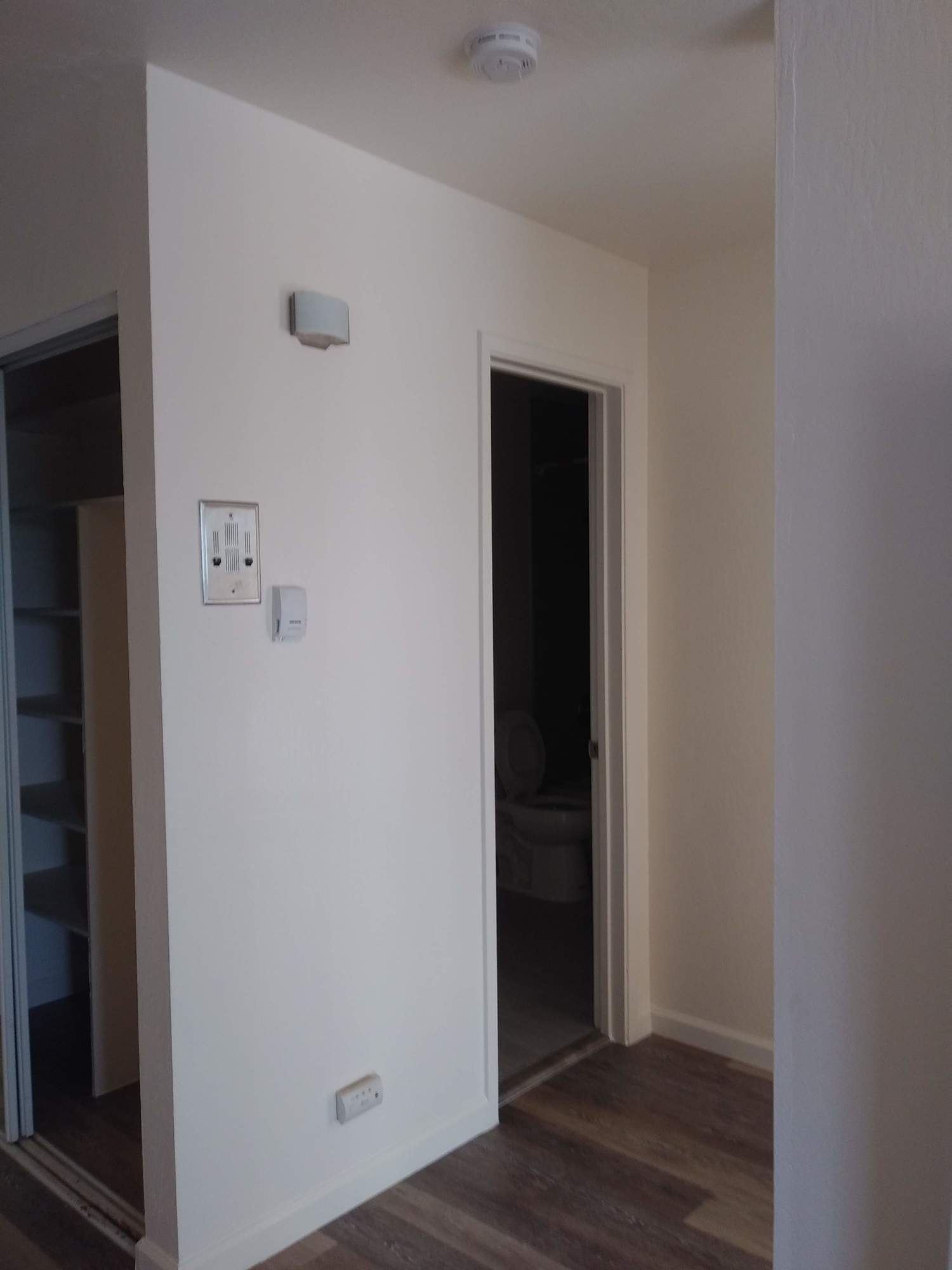 a hallway with a white wall and a door leading to a bathroom .