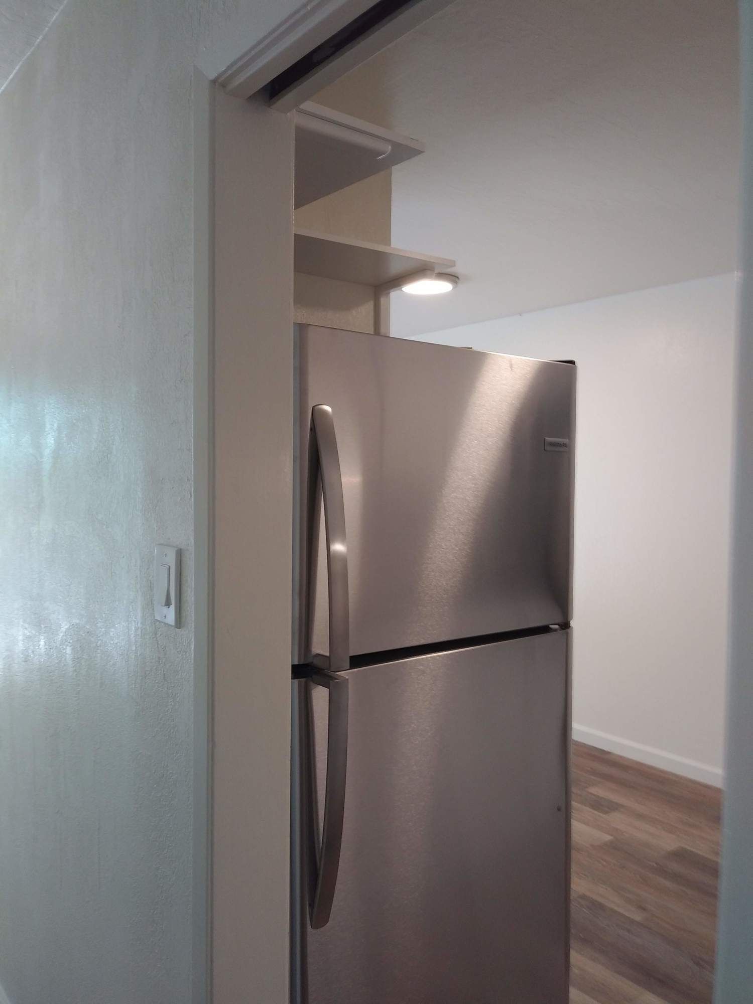 a stainless steel refrigerator is sitting in a room next to a door .