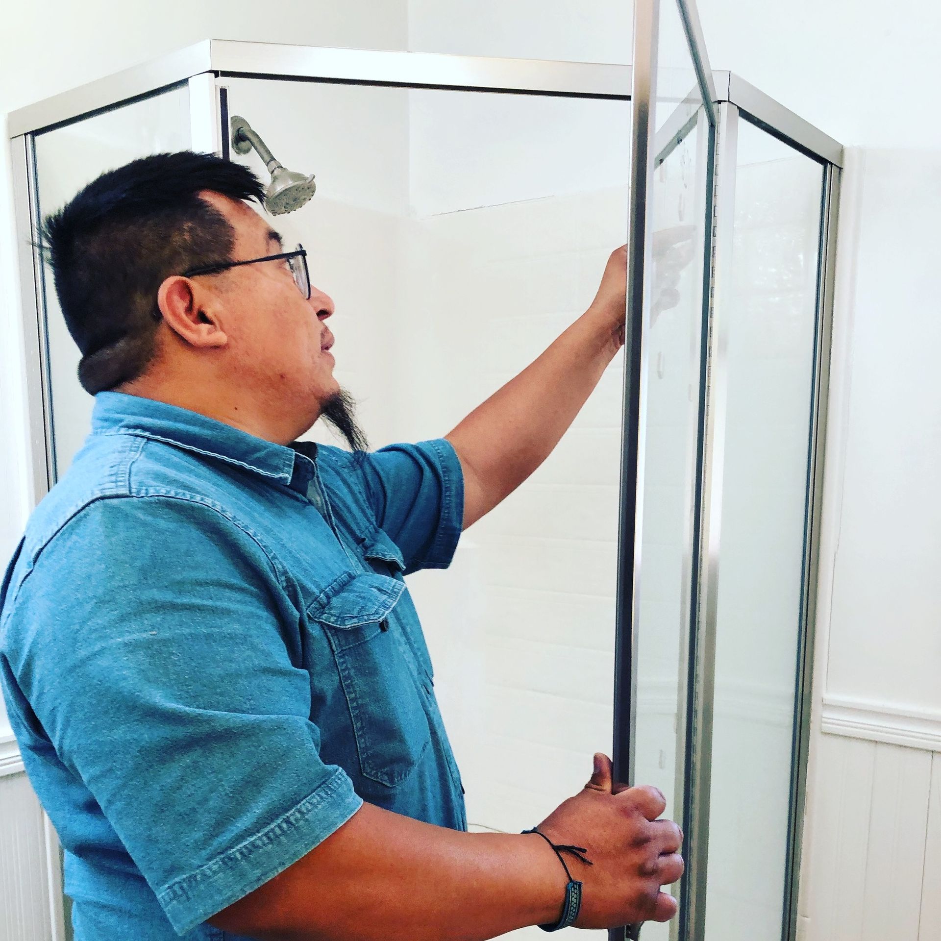 a man in a blue shirt is standing in front of a shower stall .