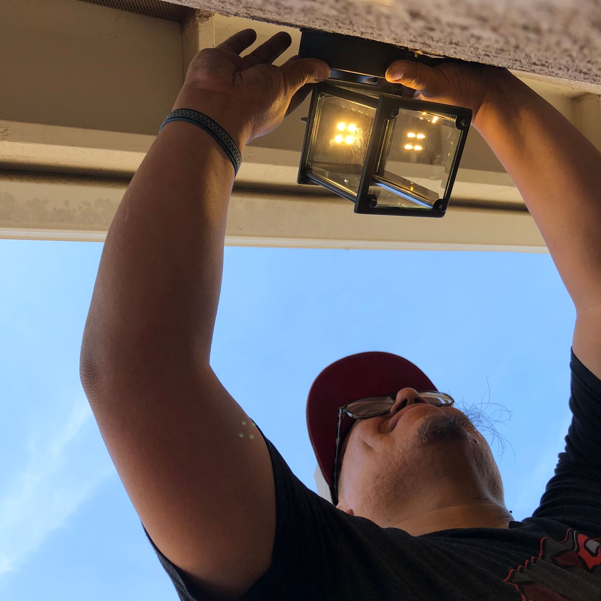 a man is reaching up to fix a light on the ceiling