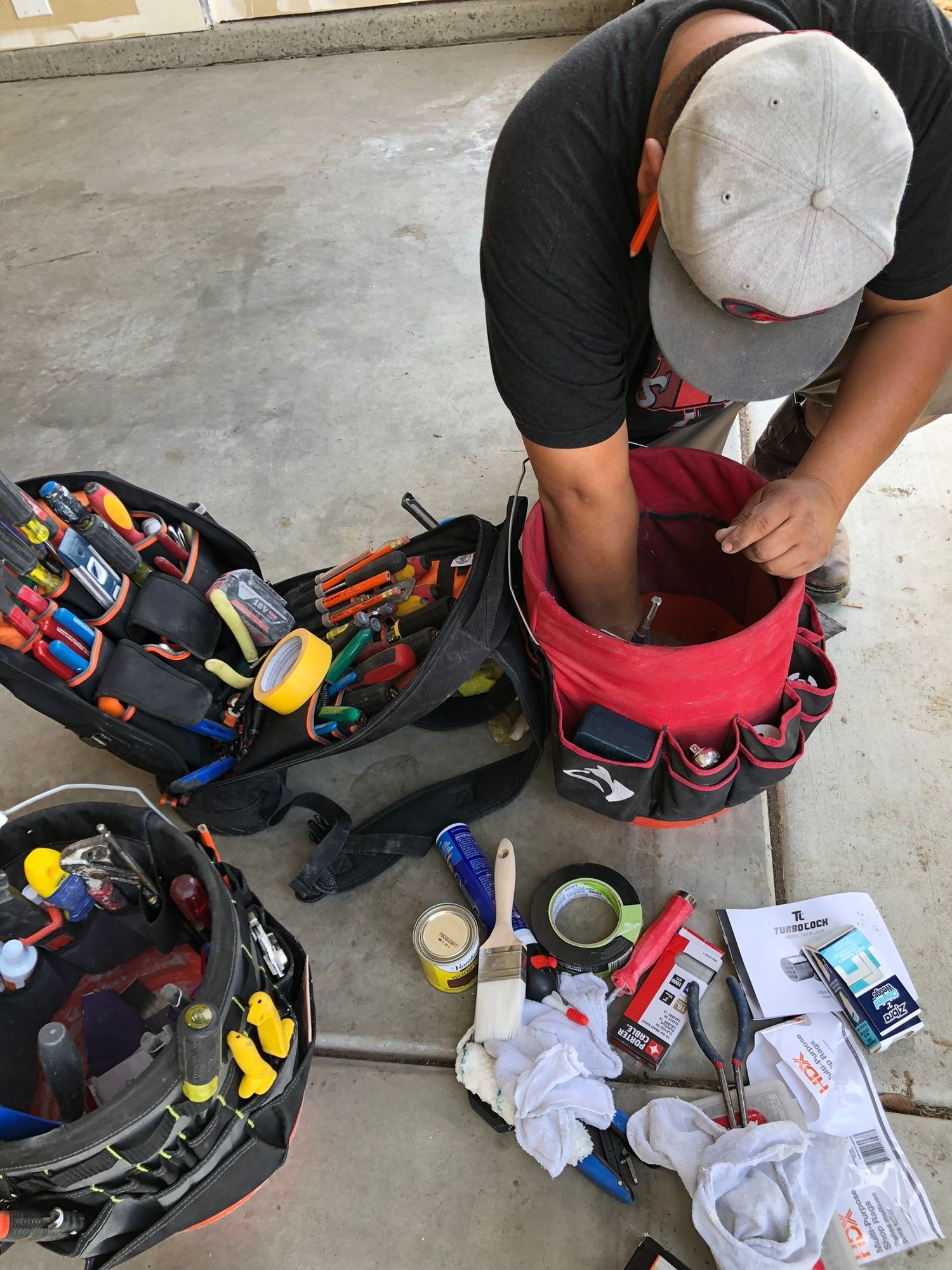 a man is kneeling down next to a bucket of tools .