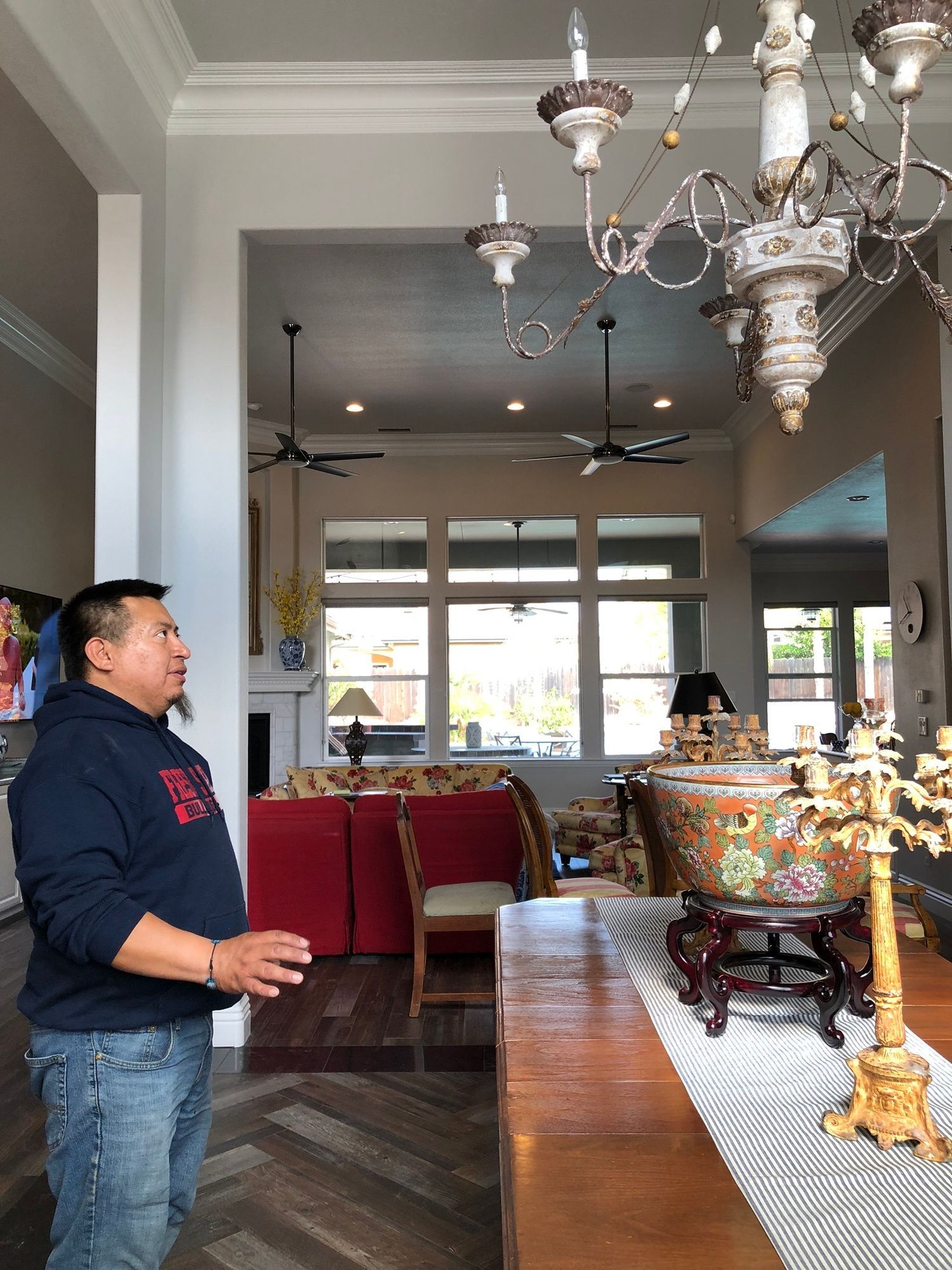 a man is standing in a living room looking at a chandelier .