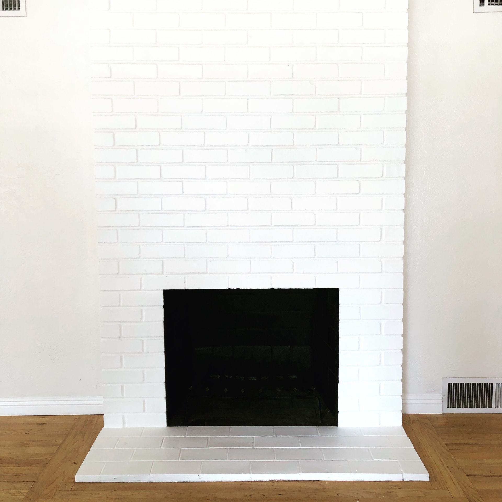 a white brick fireplace with a black screen in a living room .