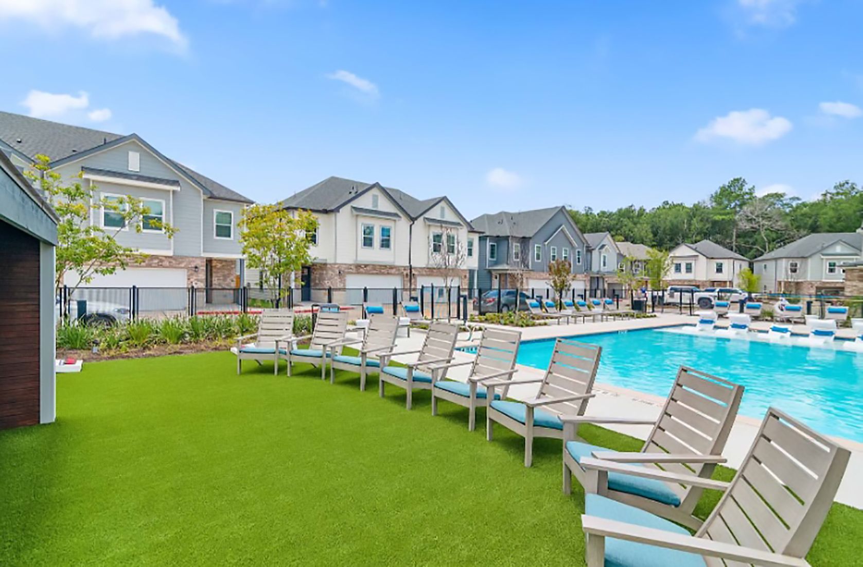 A row of chairs sitting on top of a lush green lawn next to a swimming pool.