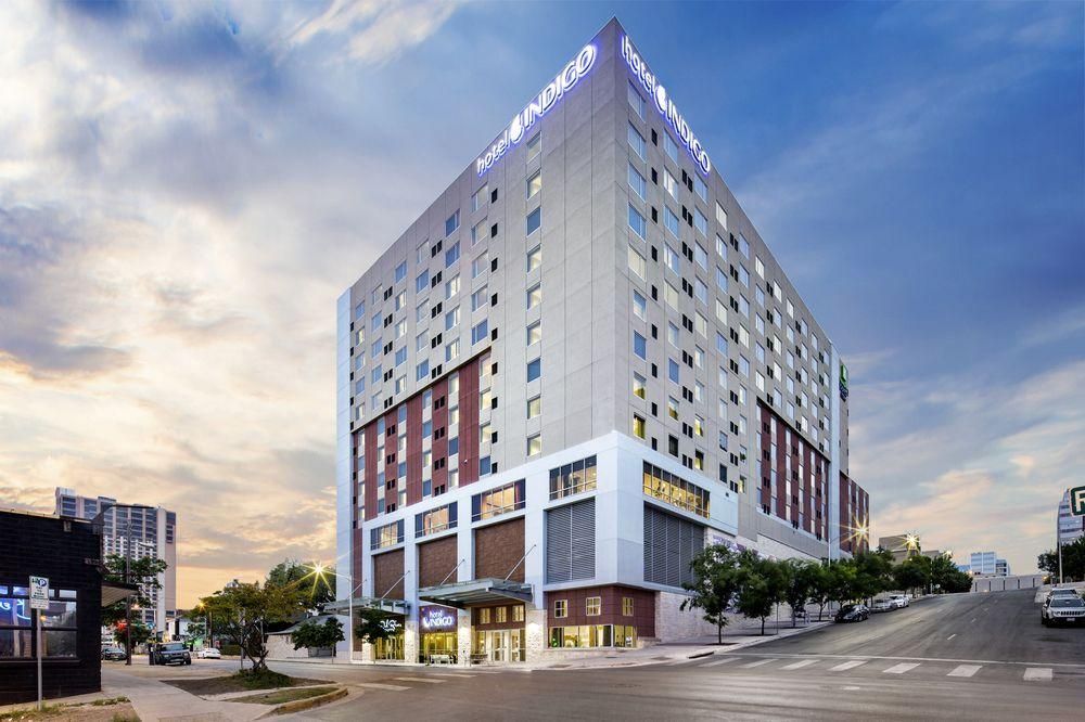 A large building with a lot of windows is sitting on the corner of a city street.