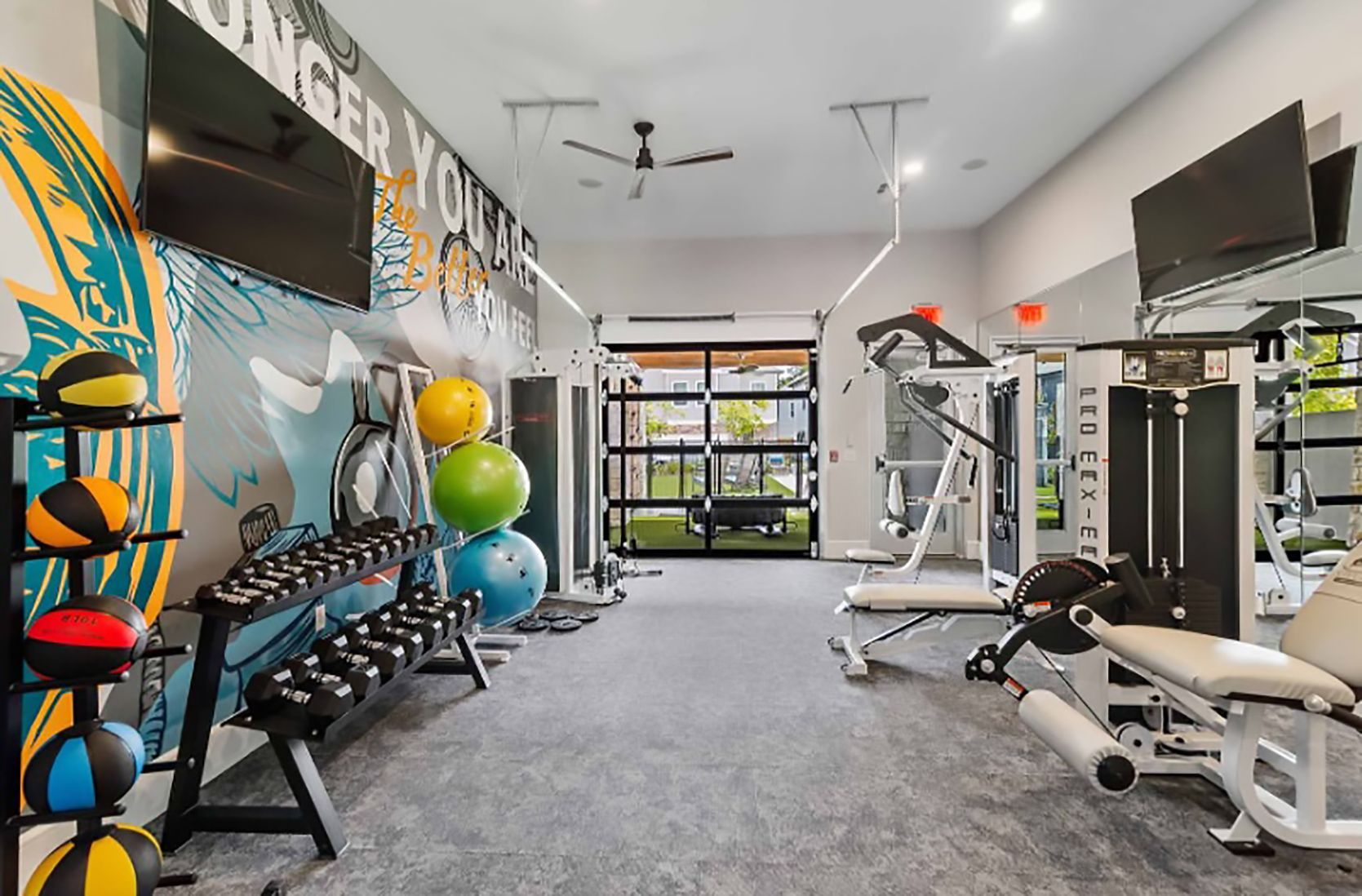 A gym with a lot of equipment and a mural on the wall.