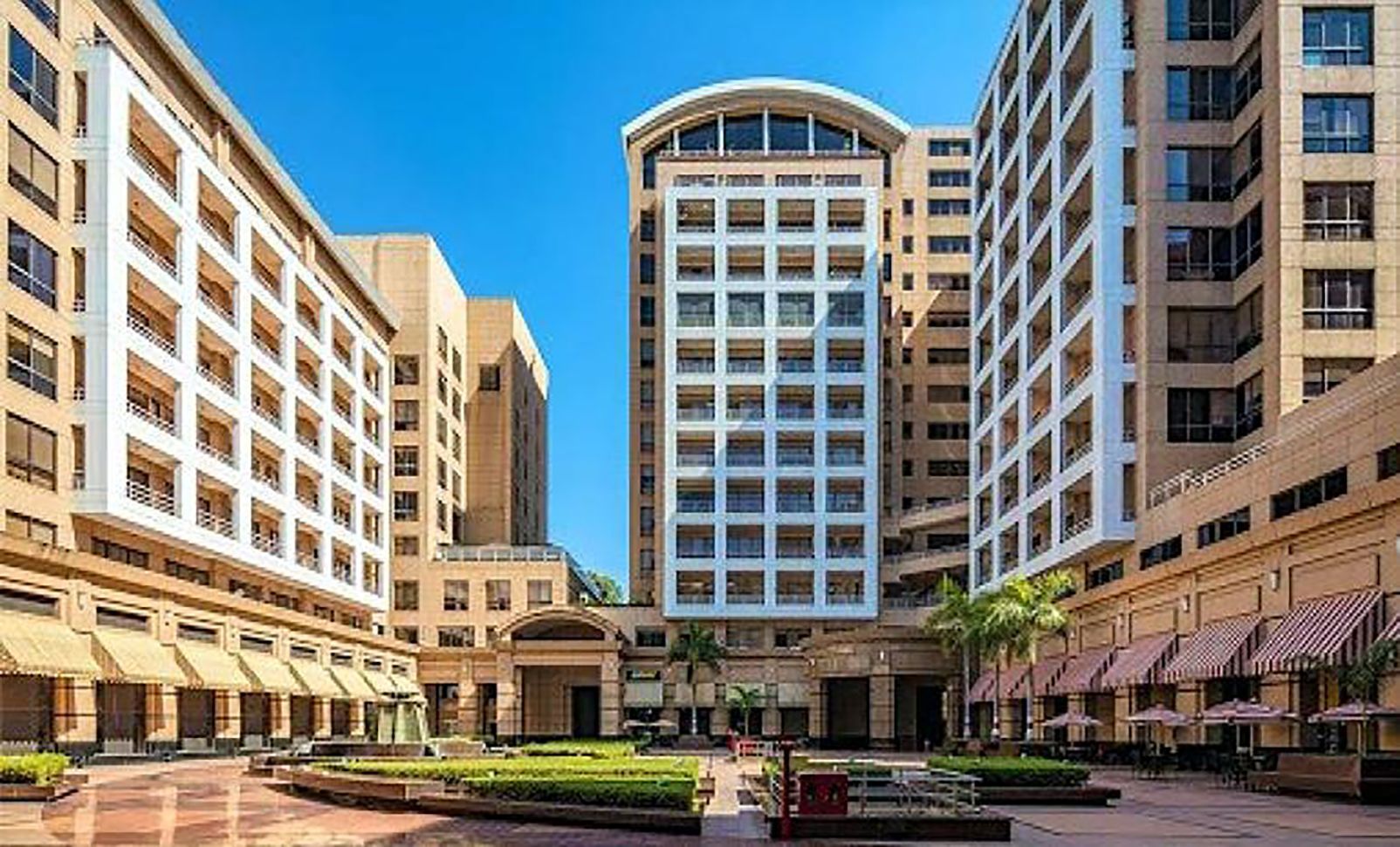 A large building with a lot of windows is surrounded by smaller buildings.