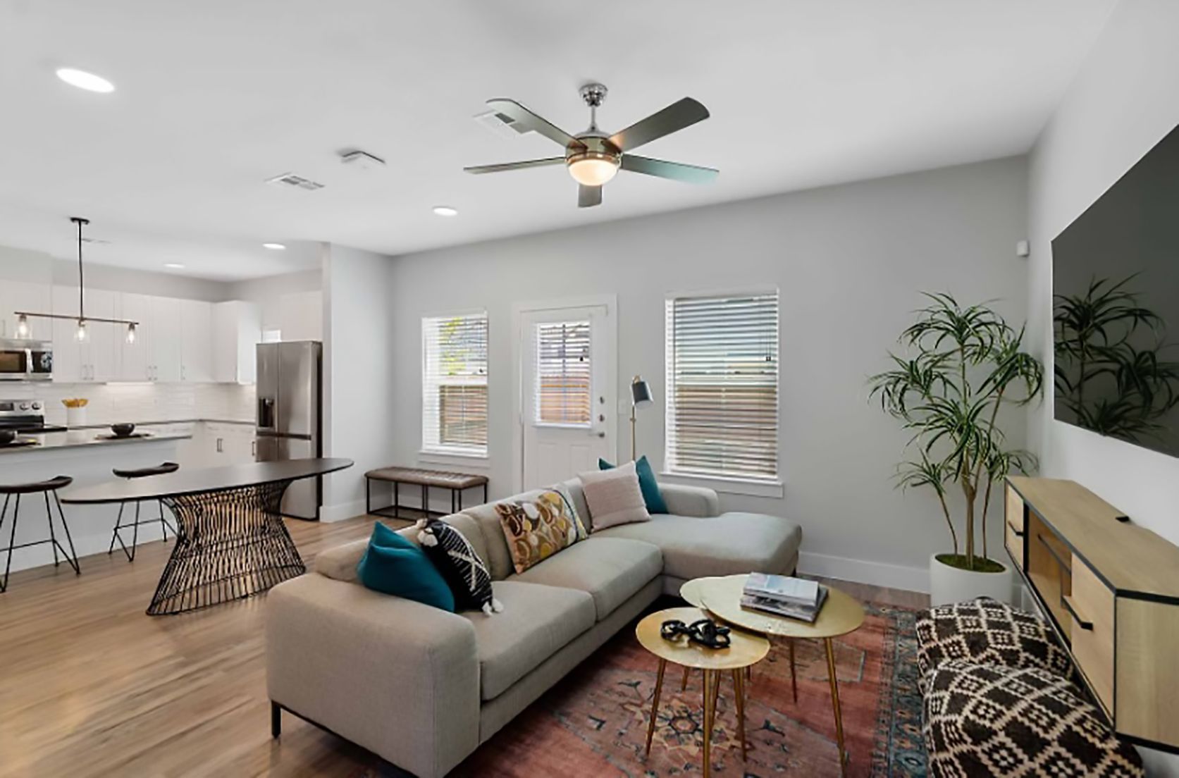 A living room with a couch , table , television and ceiling fan.