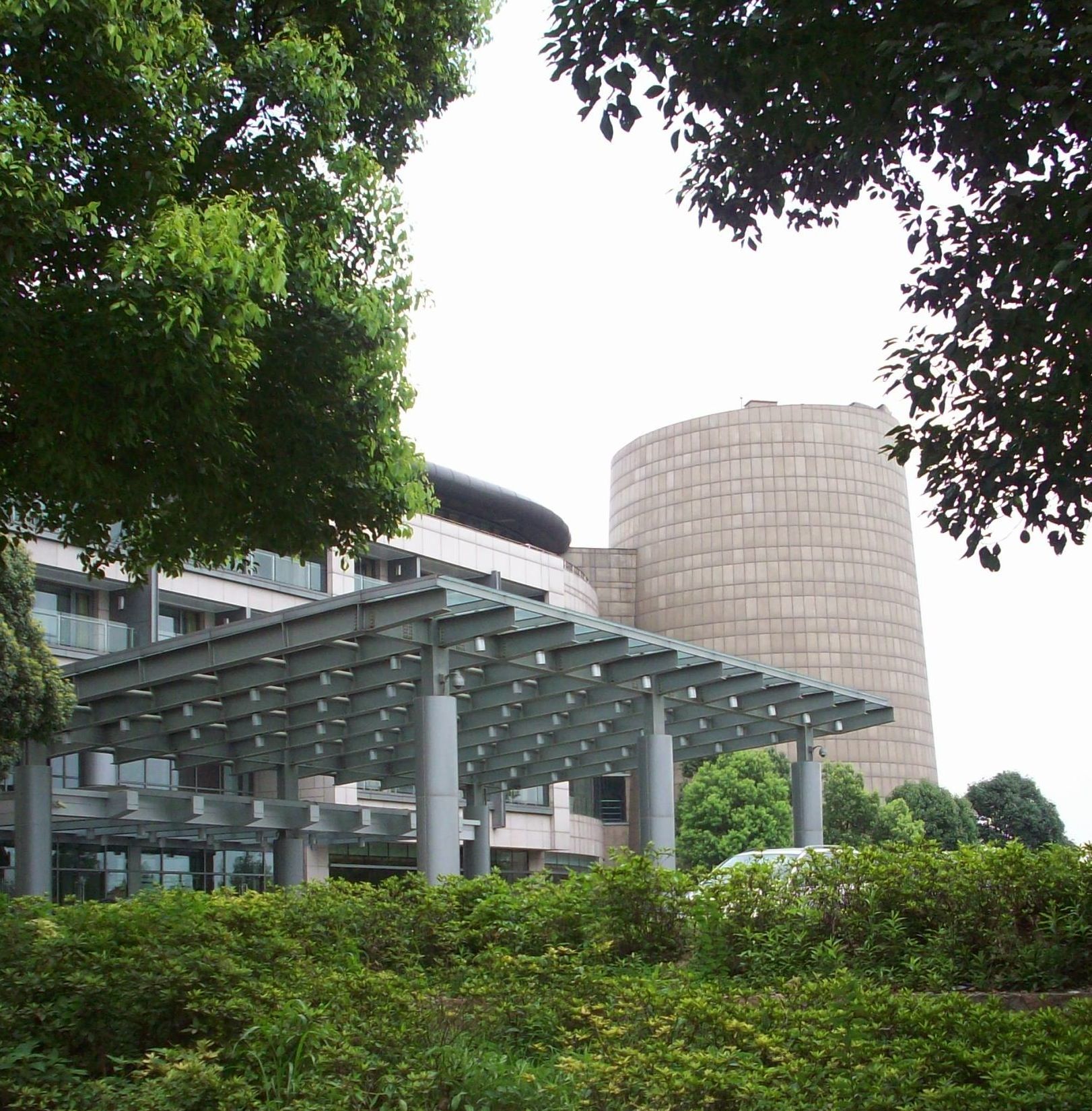 A large building with a glass roof is surrounded by trees