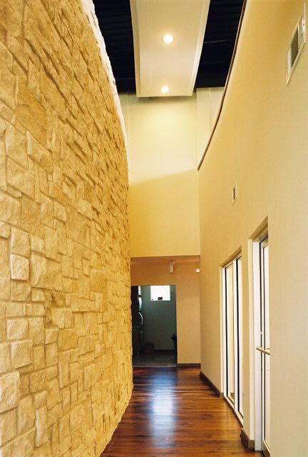 A long hallway with a brick wall and wooden floor