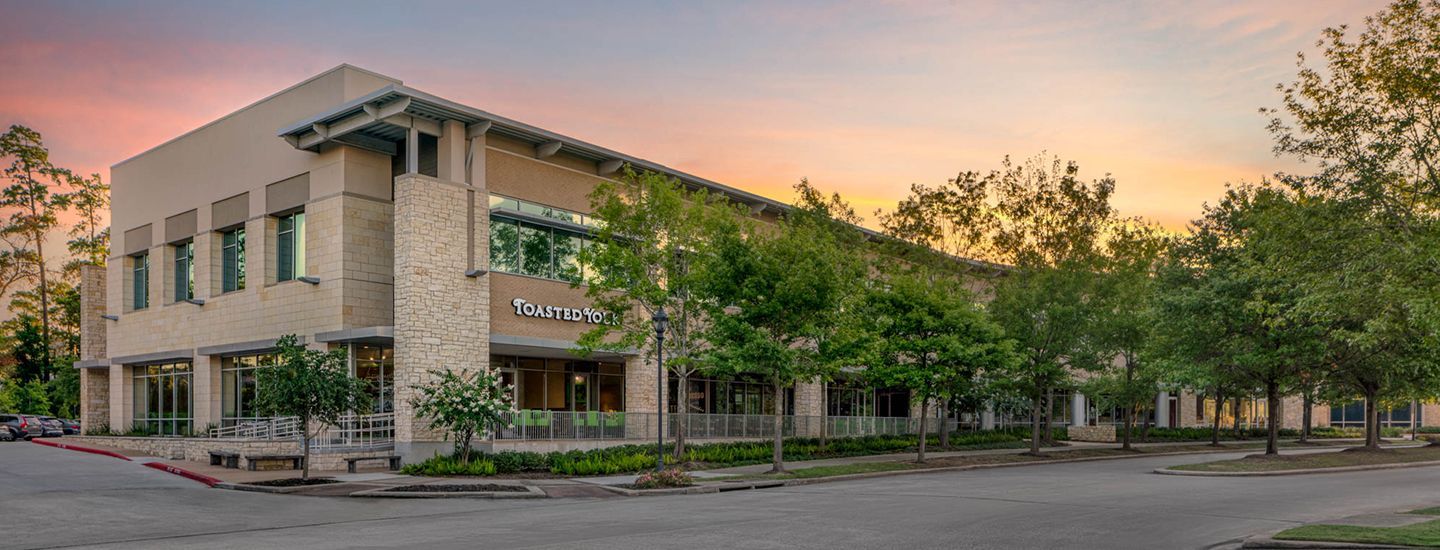 A large building with a lot of windows is surrounded by trees at sunset.