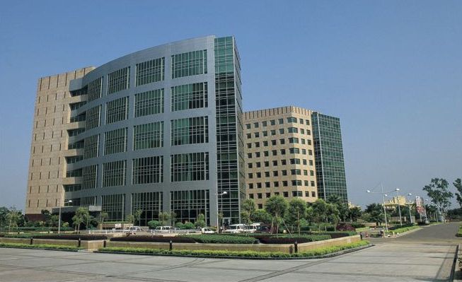 A large building with a lot of windows is surrounded by other buildings