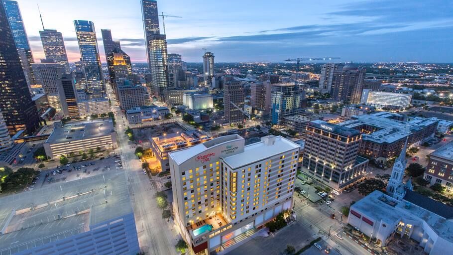 An aerial view of a city at night with a hotel in the foreground.