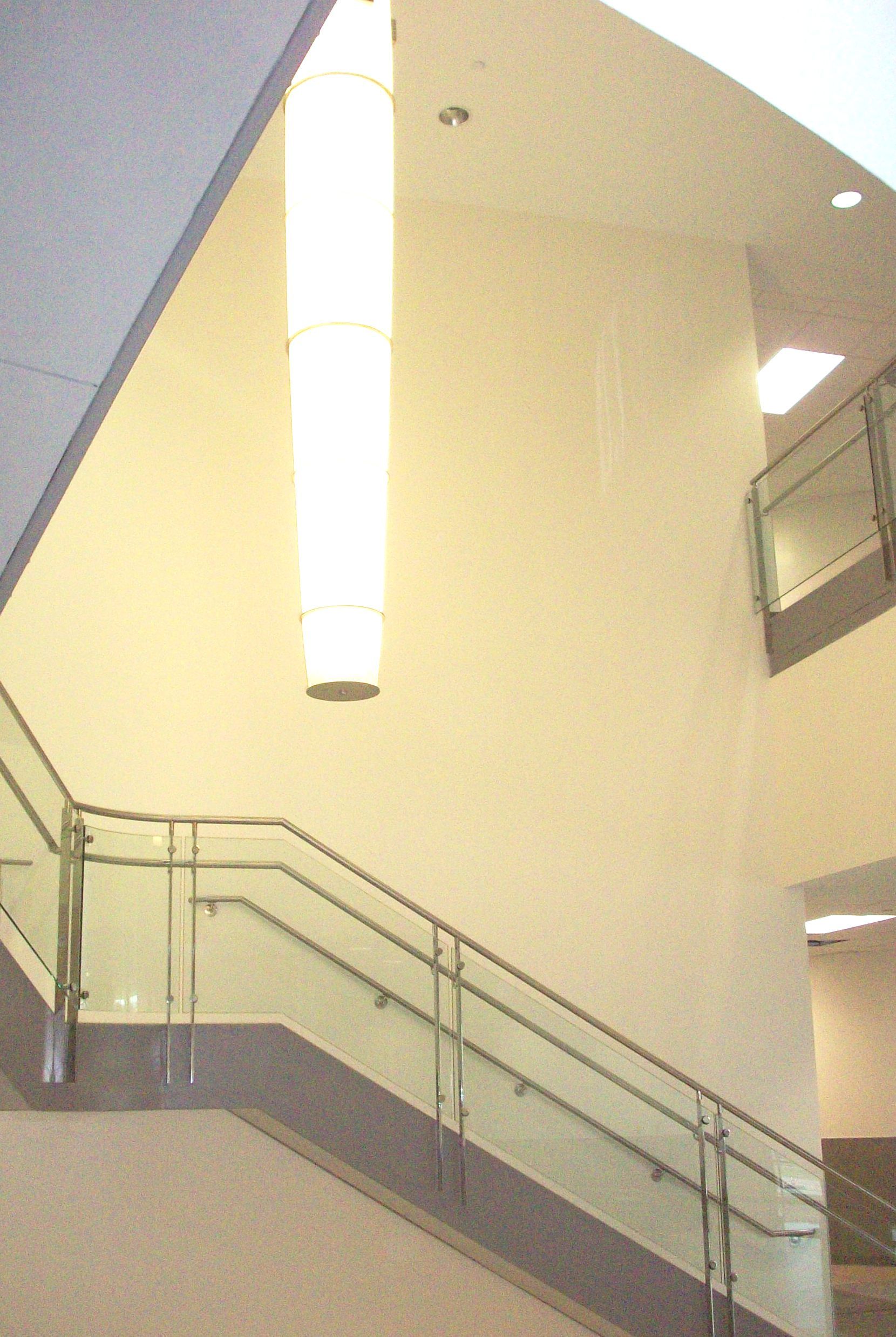 A staircase with a glass railing and a light hanging from the ceiling